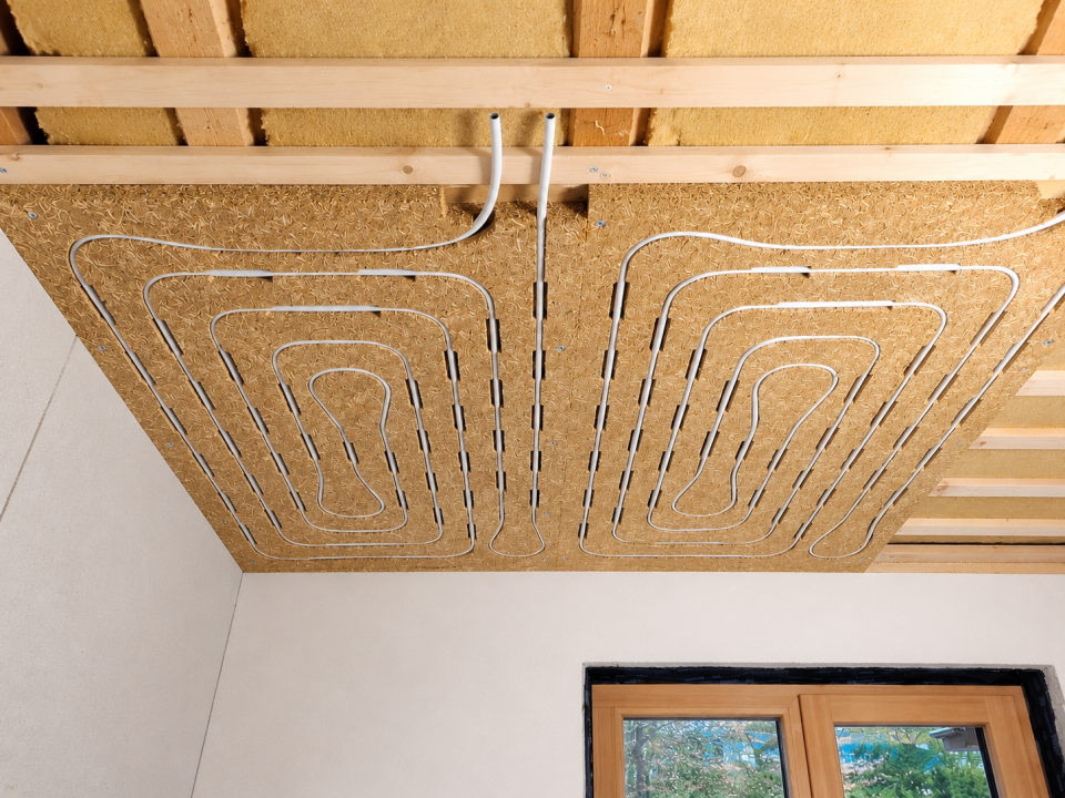 Uniwarm Healture Deckenmodul mit integrierter Fu&szlig;bodenheizungsleitung, w&auml;hrend der Montage an der Decke in einem biobasierten Sanierungsprojekt. Die Strohplatte bildet die Grundlage f&uuml;r ein energieeffizientes System zum komfortablen Heizen und K&uuml;hlen.