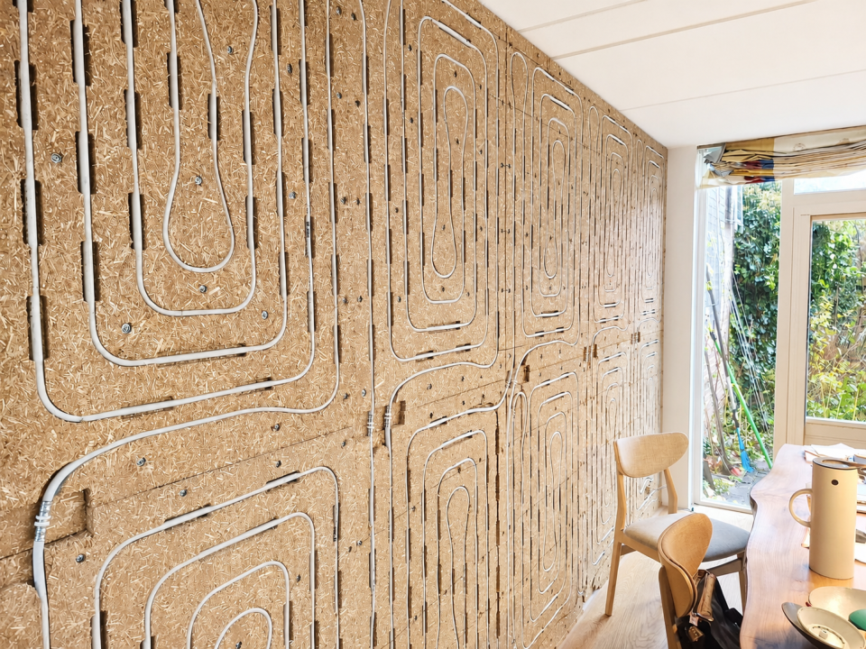 Healture Wandmodul von Uniwarm mit biobasierten Strohplatten und integrierten Heiz- und Kühlleitungen, installiert über eine komplette Wand in einem Sanierungsprojekt. Die Wandheizung ist für die Endbearbeitung vorbereitet und sorgt für angenehme Strahlun