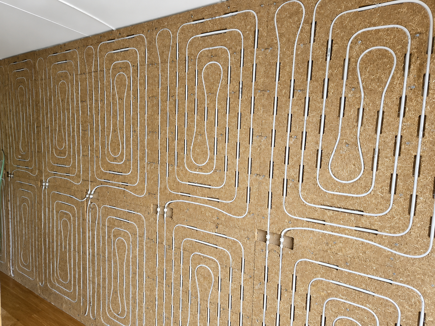 Healture Wandmodul von Uniwarm mit biobasierten Strohplatten und integrierten Heiz- und Kühlleitungen, montiert als komplette Wandinstallation.