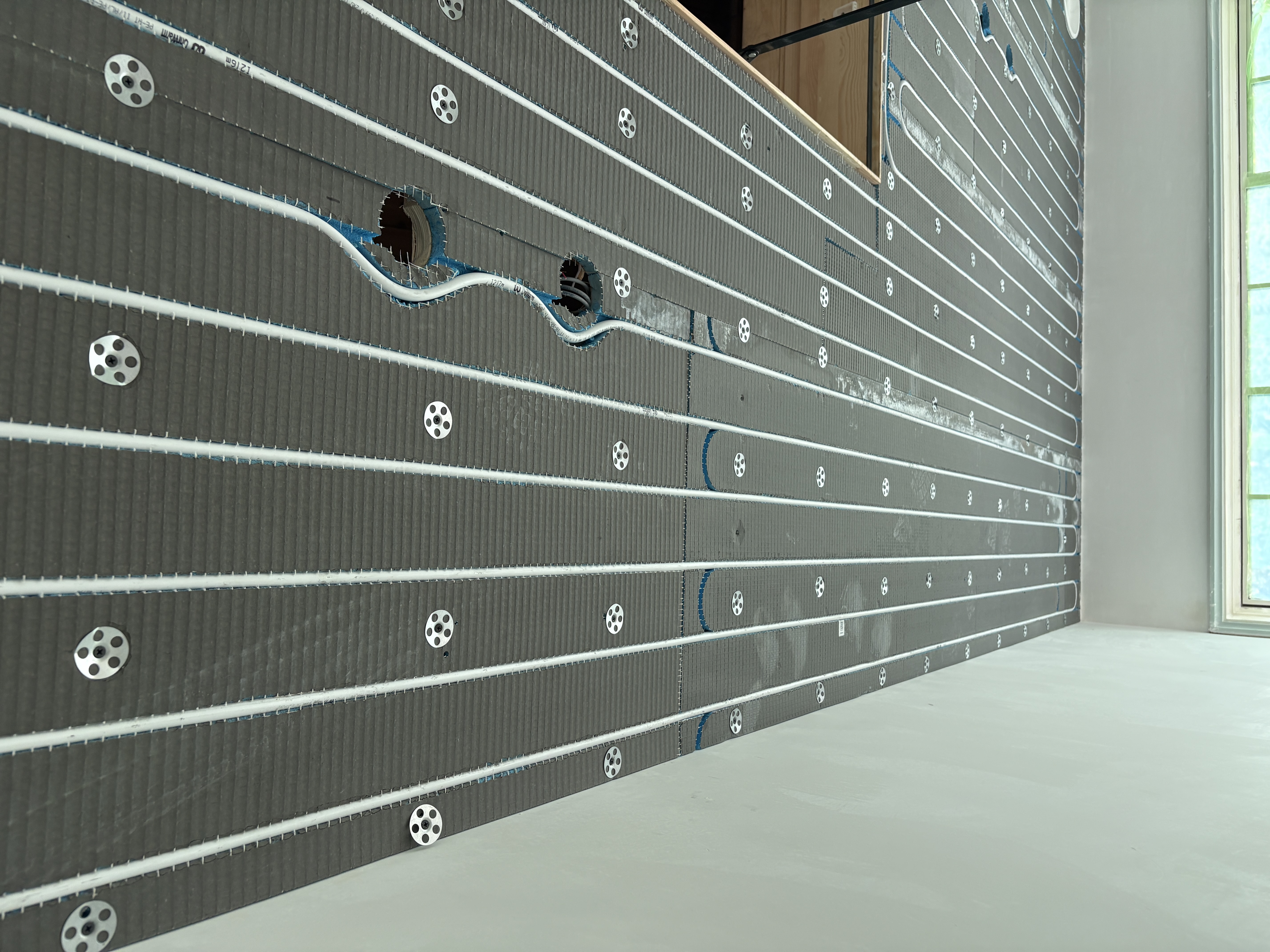 Overzicht van een koelplafond in installatie, met leidingen, bevestigingsrozetten en uitsparingen voor verlichting.