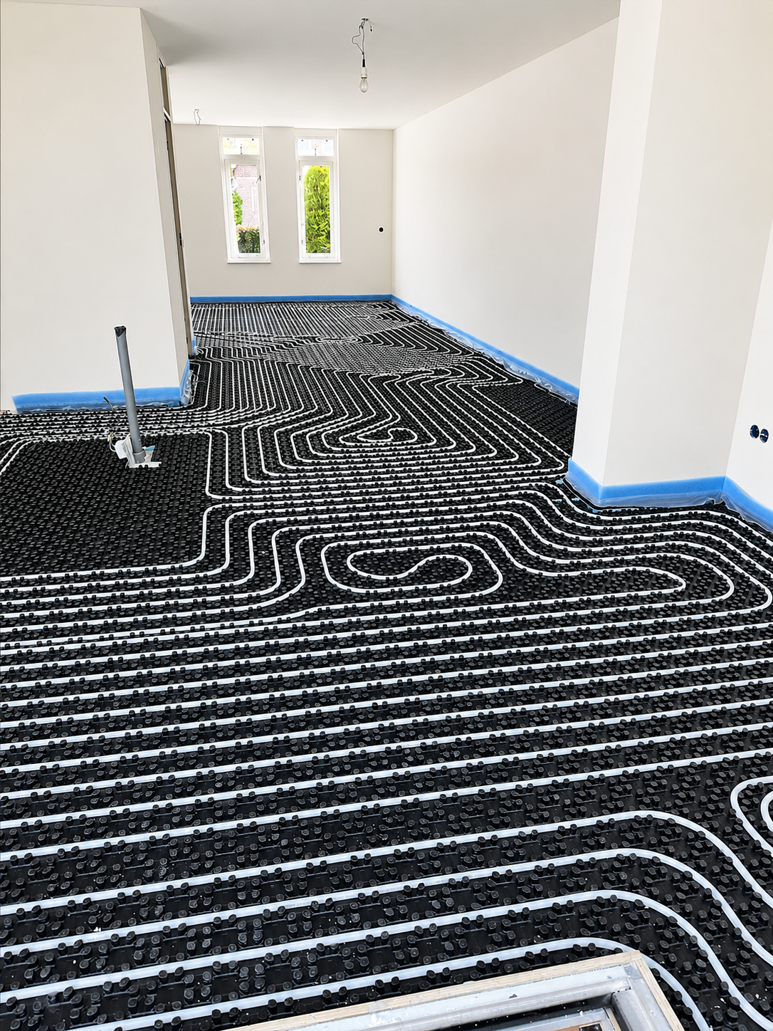 UniWarm Noppenplattensystem mit Fußbodenheizungsrohren, installiert in einem Neubau mit offenem Grundriss. Die Noppenplatten gewährleisten eine sichere Rohrfixierung und eine gleichmäßige Wärmeverteilung für höchsten Wohnkomfort.