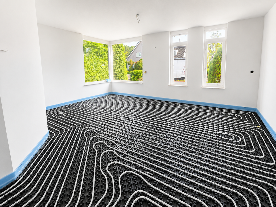 UniWarm Noppenplattensystem mit Fußbodenheizungsrohren, montiert in einem großzügigen Neubau. Das Fußbodenheizungssystem mit Noppenplatten sorgt für eine schnelle Montage, eine optimale Wärmeverteilung und eignet sich für energieeffizientes Heizen und Küh