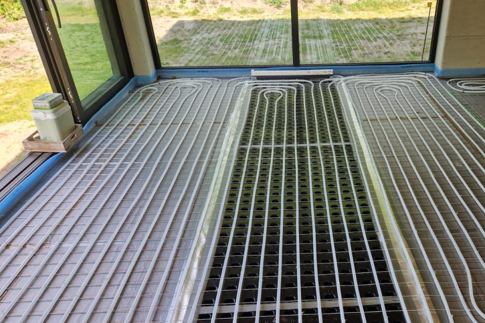 Uniwarm Lüftungsboden mit Lüftungsnoppenplatten und integrierten Rohrleitungen, installiert im Wohnbereich eines Neubaus. Das System verteilt die Zuluft gleichmäßig und trägt zu einem energieeffizienten und komfortablen Raumklima bei.