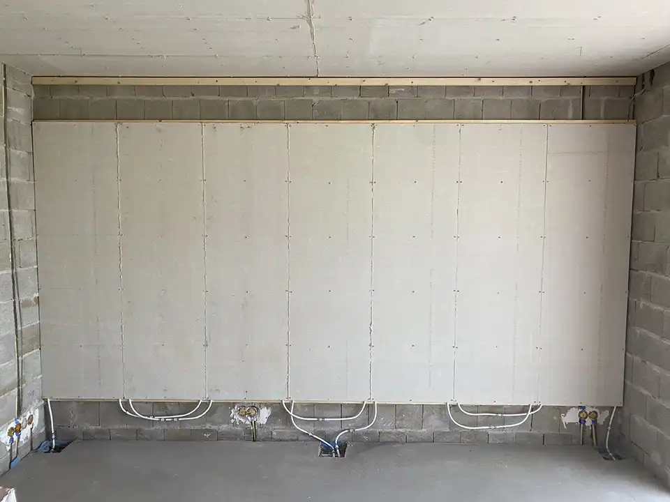 Vollständig bedeckte Wand mit Wandheizplatten, die Leitungen sind sichtbar, aber noch nicht angeschlossen